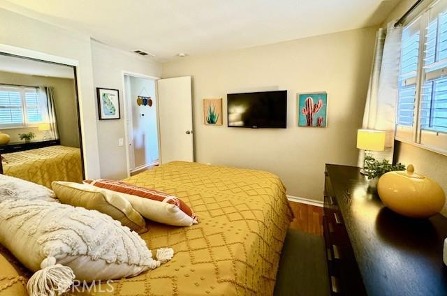 bedroom featuring a closet, visible vents, dark wood-type flooring, and baseboards