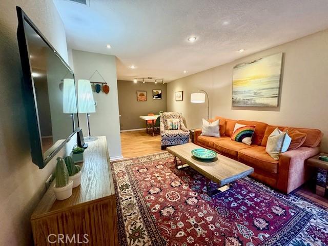 living area with track lighting, recessed lighting, and wood finished floors