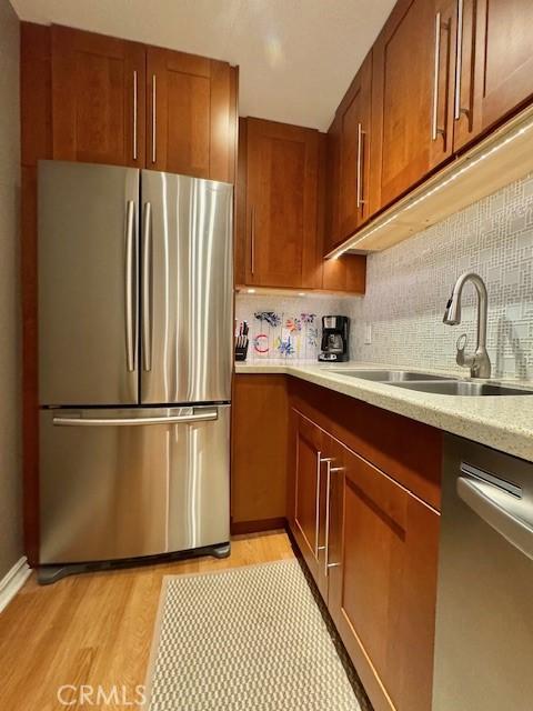 kitchen featuring backsplash, brown cabinets, appliances with stainless steel finishes, and a sink