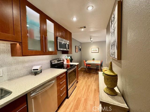 kitchen featuring light wood-style flooring, visible vents, backsplash, and stainless steel appliances