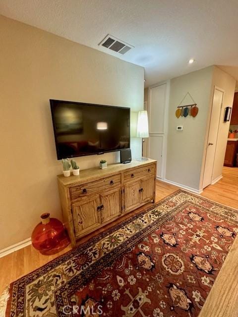 living area featuring visible vents, baseboards, and light wood-style floors