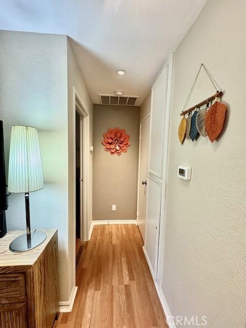 corridor featuring light wood-style floors, visible vents, and baseboards