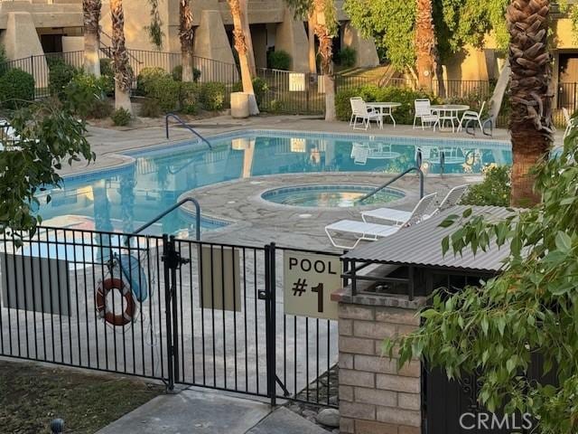 community pool featuring a patio, fence, and a hot tub