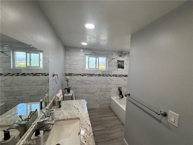 bathroom with hardwood / wood-style floors, vanity, tile walls, and a healthy amount of sunlight