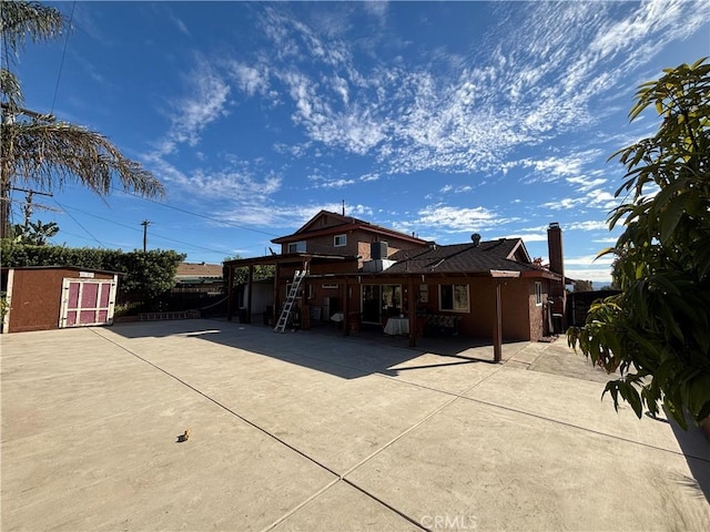 view of front of home with a storage unit and a patio