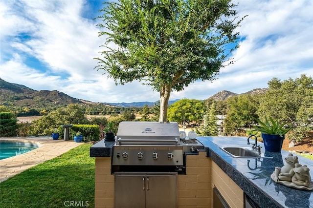 view of patio featuring a sink, a mountain view, an outdoor pool, and area for grilling