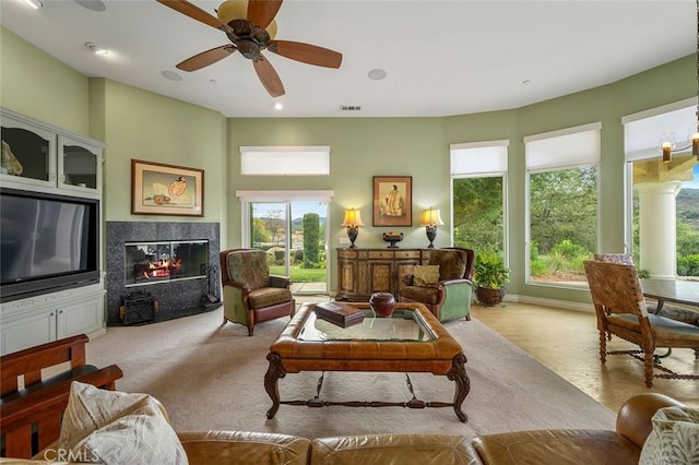 living room with visible vents, ceiling fan with notable chandelier, a high end fireplace, recessed lighting, and baseboards