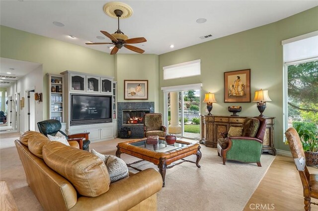 living room featuring ceiling fan, a fireplace, and light hardwood / wood-style floors