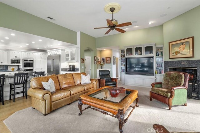 living area with visible vents, a ceiling fan, recessed lighting, arched walkways, and a premium fireplace