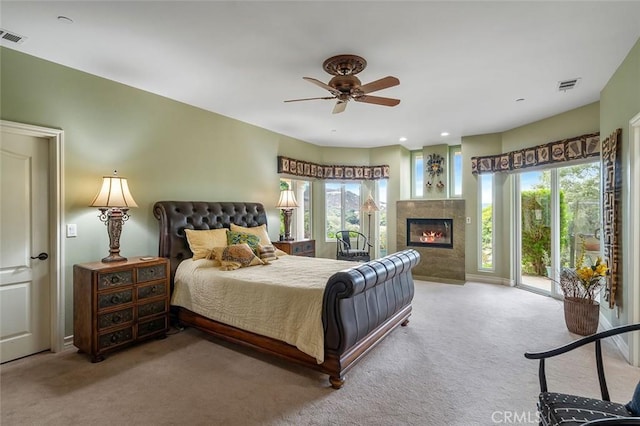 carpeted bedroom featuring visible vents, multiple windows, a glass covered fireplace, and access to outside