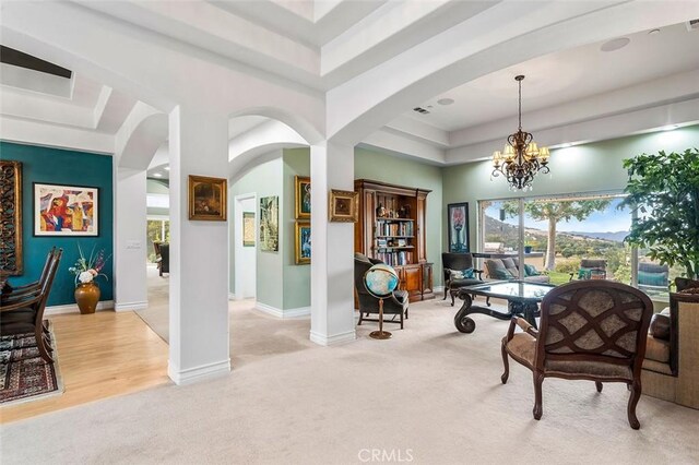 sitting room with a tray ceiling, light colored carpet, and a notable chandelier