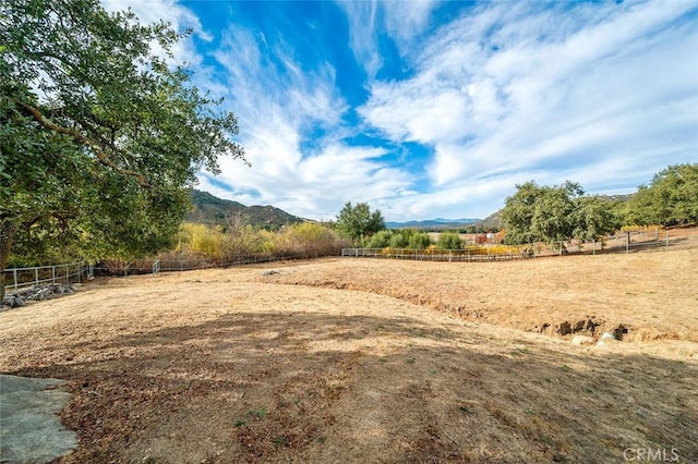 view of yard featuring a mountain view, a rural view, and fence