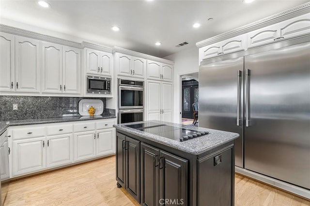 kitchen with built in appliances, white cabinets, and light wood-type flooring