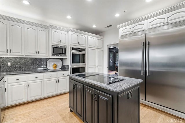 kitchen with built in appliances, white cabinetry, light wood-style floors, and visible vents