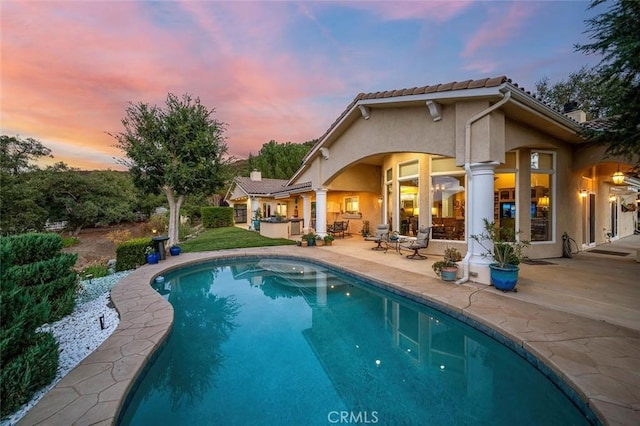 back house at dusk with a patio and an outdoor kitchen