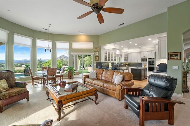 living room with a mountain view and ceiling fan with notable chandelier