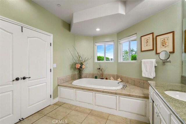 bathroom with tile patterned flooring, vanity, and a tub