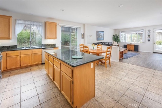 kitchen with dishwasher, a kitchen island, dark stone countertops, and light wood-type flooring