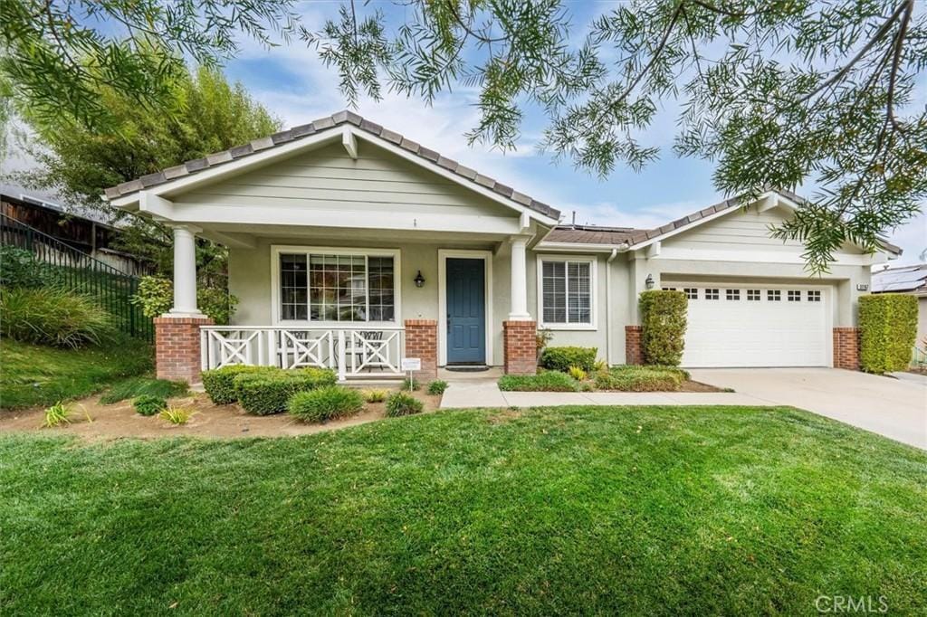 view of front of property with a garage, a porch, and a front lawn