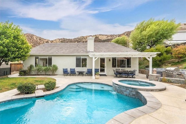 back of property with a mountain view, a swimming pool with hot tub, a patio area, and area for grilling