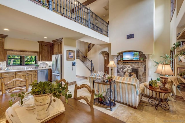 dining space featuring a stone fireplace and a towering ceiling