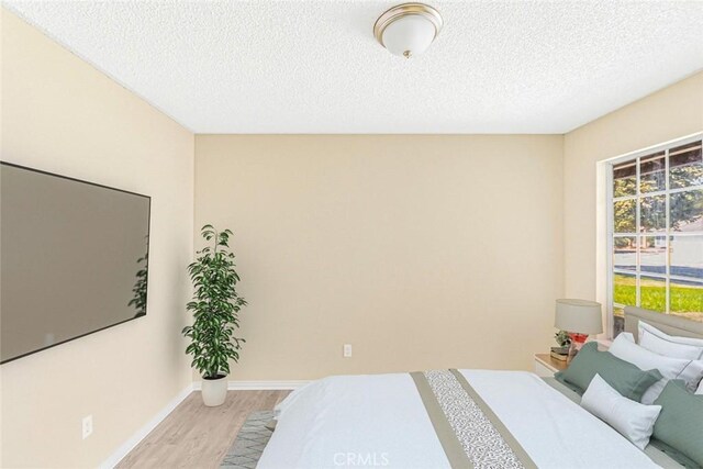 bedroom with a textured ceiling and light wood-type flooring