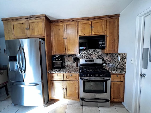 kitchen with decorative backsplash, light tile patterned floors, light stone counters, and appliances with stainless steel finishes