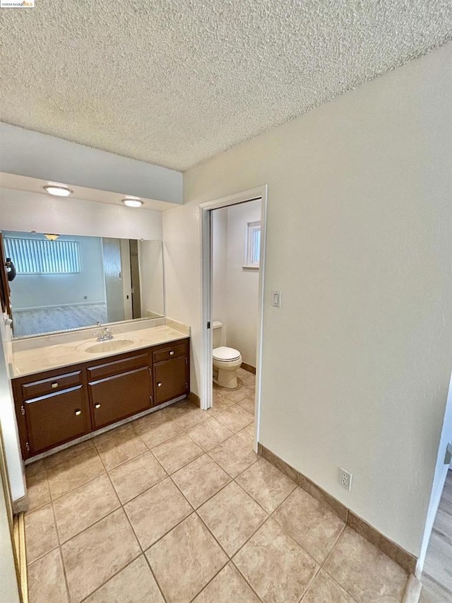 bathroom featuring tile patterned floors, vanity, a textured ceiling, and toilet