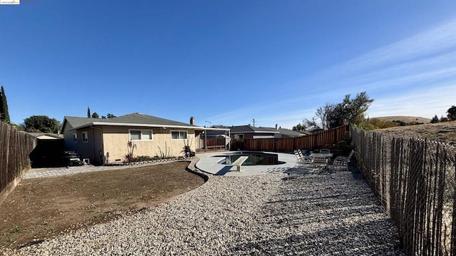 back of house with a patio and an empty pool