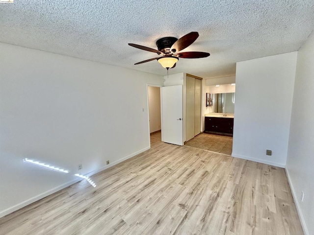 empty room featuring ceiling fan, light hardwood / wood-style floors, and a textured ceiling