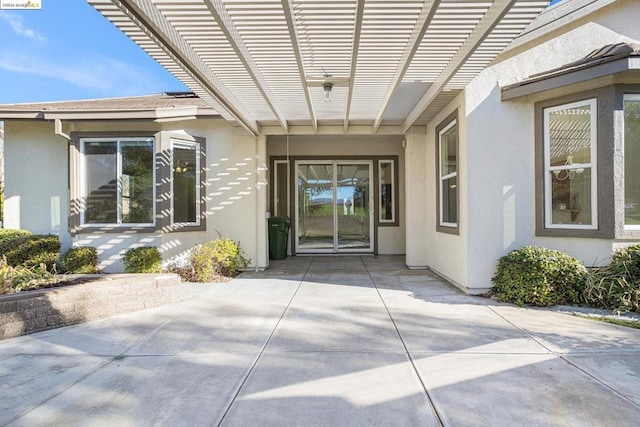 view of exterior entry featuring a pergola and a patio