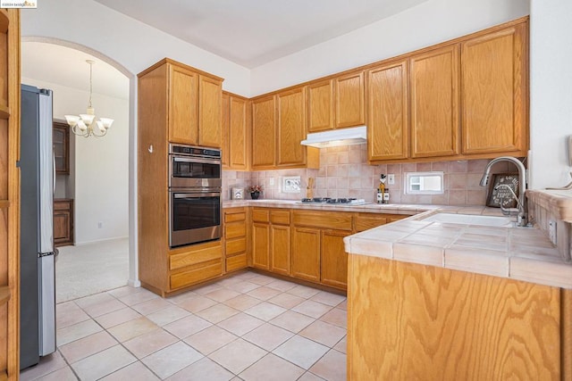 kitchen with backsplash, stainless steel appliances, sink, pendant lighting, and light tile patterned floors