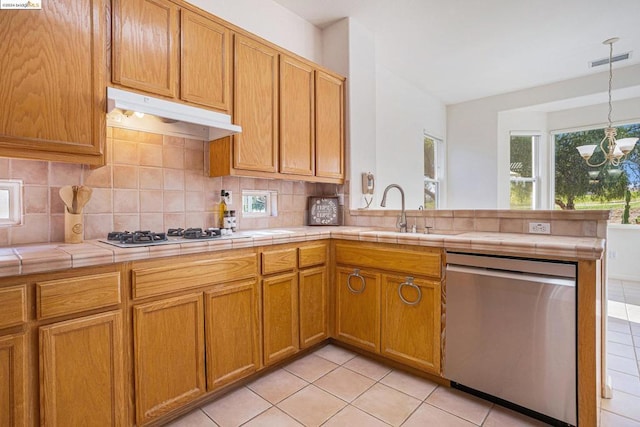 kitchen featuring sink, stainless steel dishwasher, light tile patterned floors, tile counters, and a chandelier