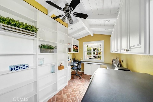 interior space featuring vaulted ceiling with beams, ceiling fan, built in desk, and wooden ceiling