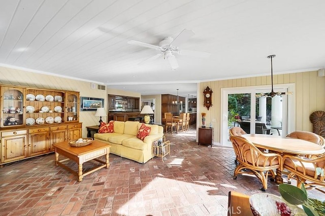 living room featuring ceiling fan, crown molding, and wood walls