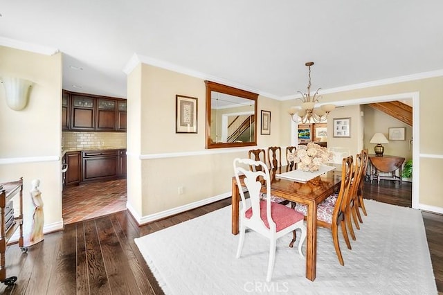 dining area with dark hardwood / wood-style floors, an inviting chandelier, and ornamental molding