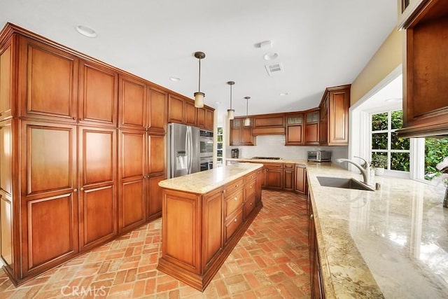 kitchen featuring light stone counters, sink, decorative light fixtures, and appliances with stainless steel finishes