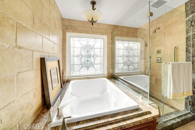 bathroom featuring shower with separate bathtub and tile walls