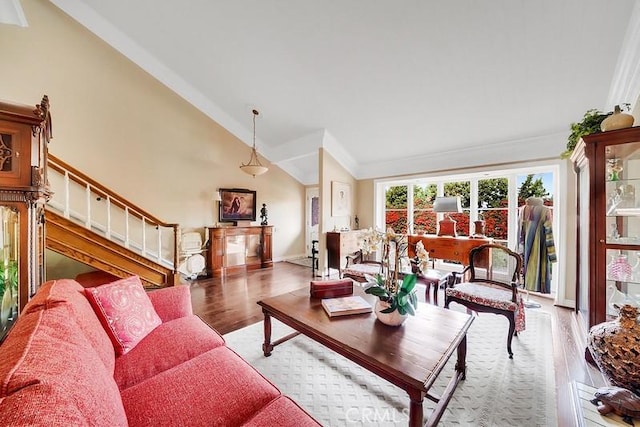 living room with wood-type flooring, ornamental molding, and high vaulted ceiling