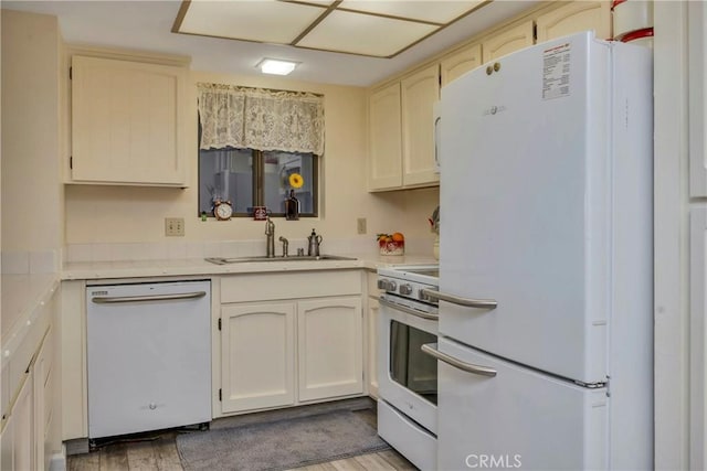 kitchen with light wood-type flooring, white appliances, and sink