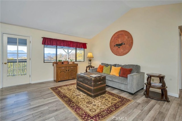 living room featuring plenty of natural light, light wood-type flooring, and lofted ceiling