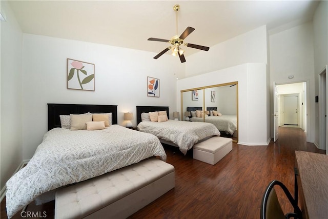 bedroom featuring ceiling fan, dark hardwood / wood-style flooring, a closet, and a high ceiling