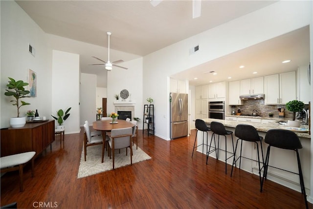 dining space with dark hardwood / wood-style floors, ceiling fan, and a high ceiling