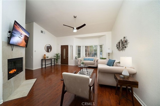 living room with ceiling fan, dark hardwood / wood-style floors, high vaulted ceiling, and a tile fireplace