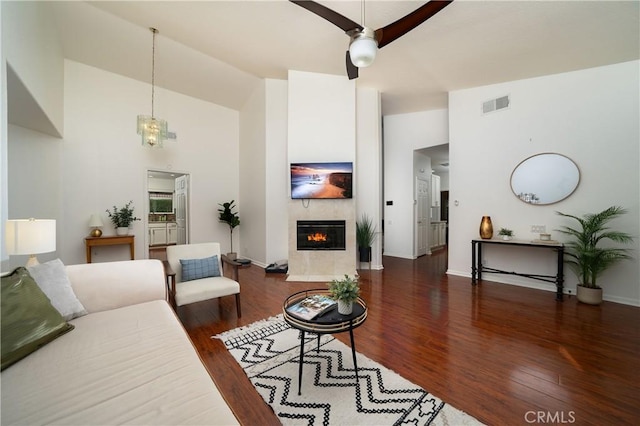 living room with a fireplace, dark hardwood / wood-style flooring, and high vaulted ceiling