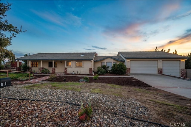 ranch-style house with a garage, concrete driveway, and stucco siding