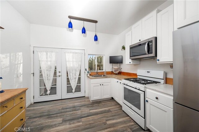 kitchen with white cabinetry, dark hardwood / wood-style flooring, decorative light fixtures, and appliances with stainless steel finishes