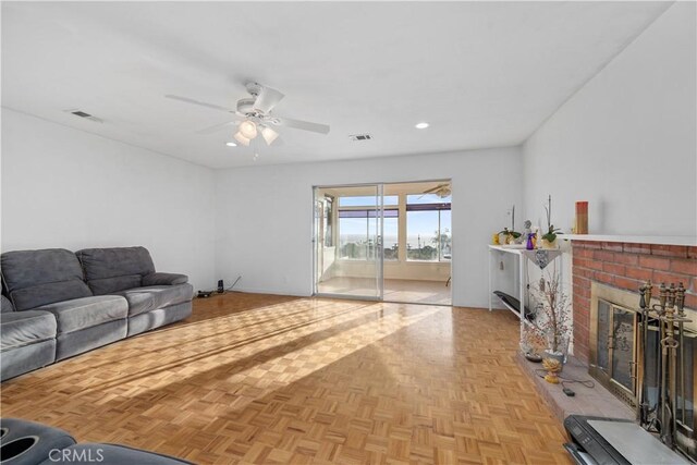 living room with ceiling fan, light parquet floors, and a brick fireplace