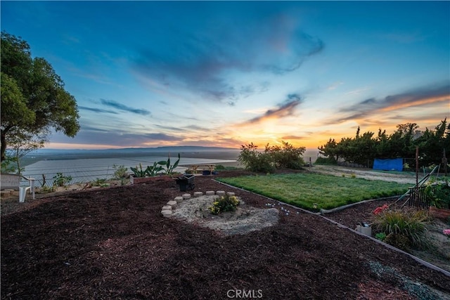 yard at dusk featuring a water view