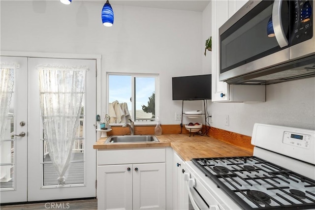 kitchen featuring wooden counters, white cabinets, sink, white gas range, and wood-type flooring